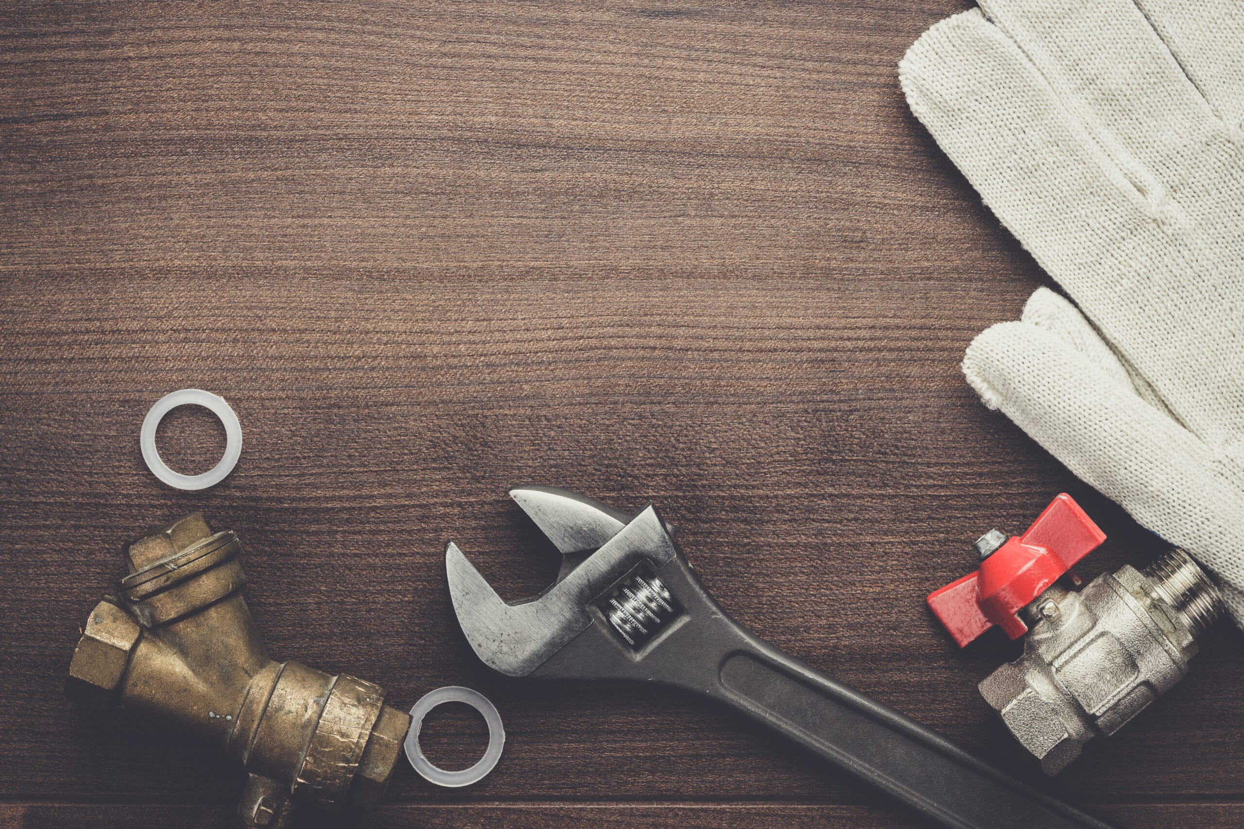 Bovenaanzichtfoto van loodgietersgereedschap op een houten achtergrond met ruimte voor tekst.